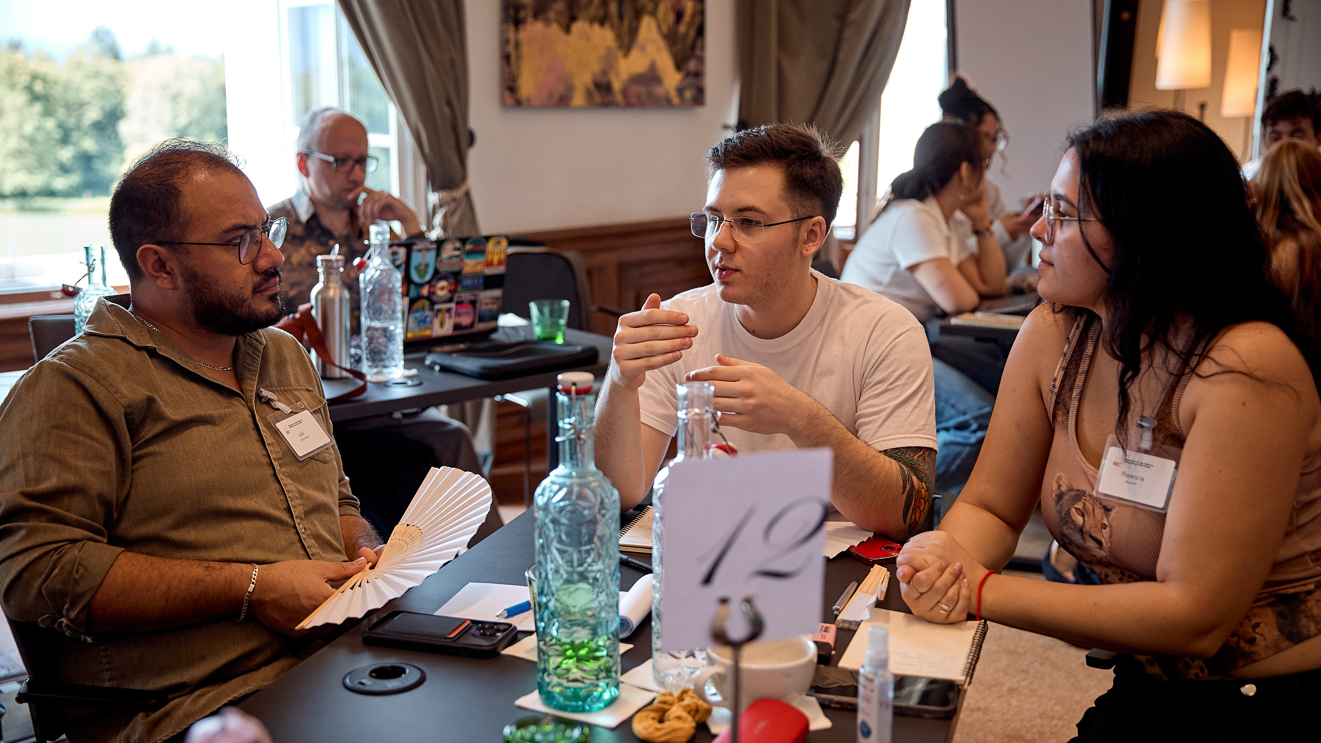 Three individuals sit at a table and engage in a lively conversation.