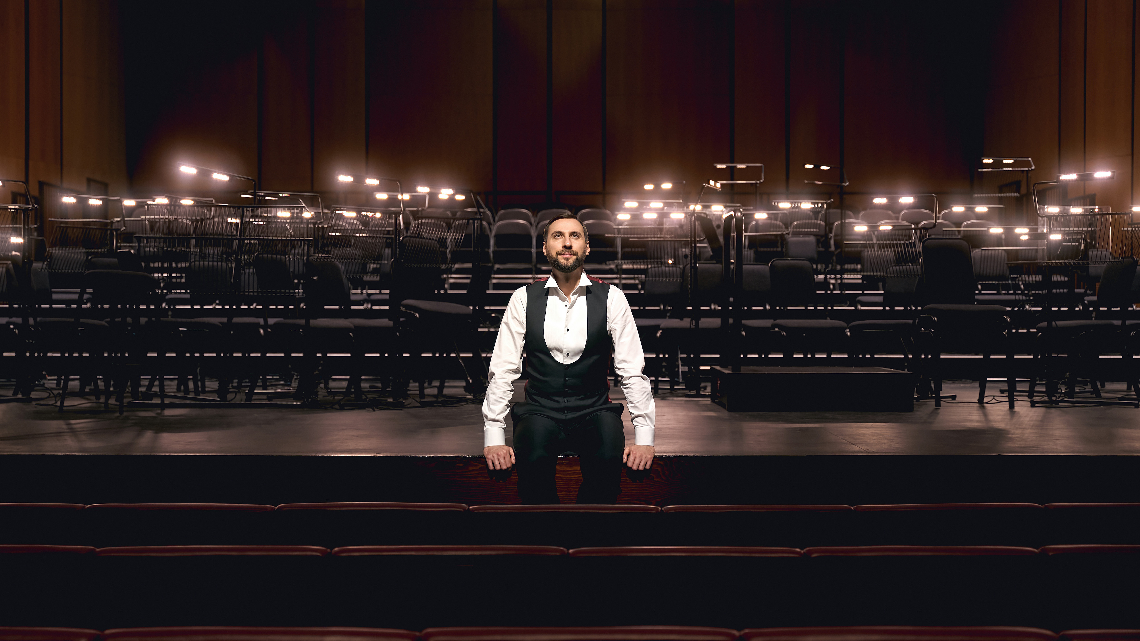 Paolo Petrocelli seated on stage gazing upwards at the Dubai Opera