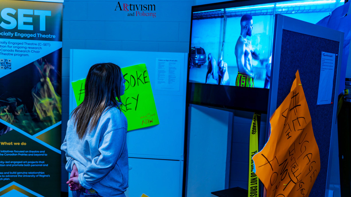 A girl views an art exhibition at the “Ar(c)tivism and Policing Exhibition,” presented at the Festival of Arts and Discourse in November 2024 at the University of Regina.