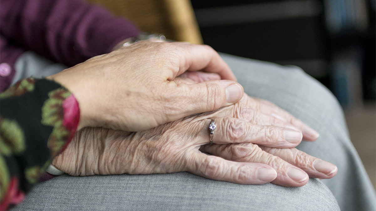 two hands of older people lay on top of each other
