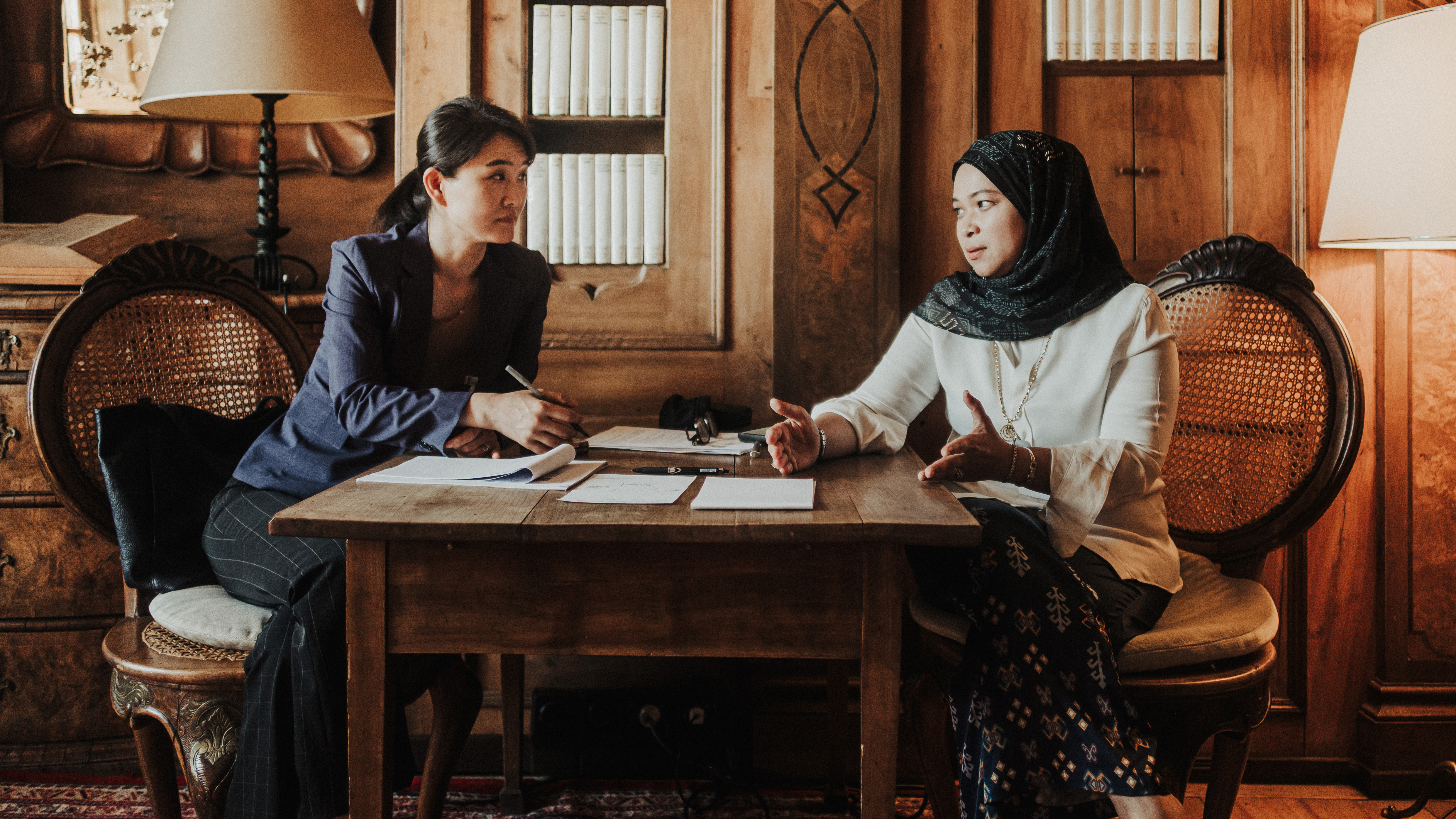 Two women engaged in a collaborative discussion while seated at a table in the Max Reinhardt Library of Schloss Leopoldskron.