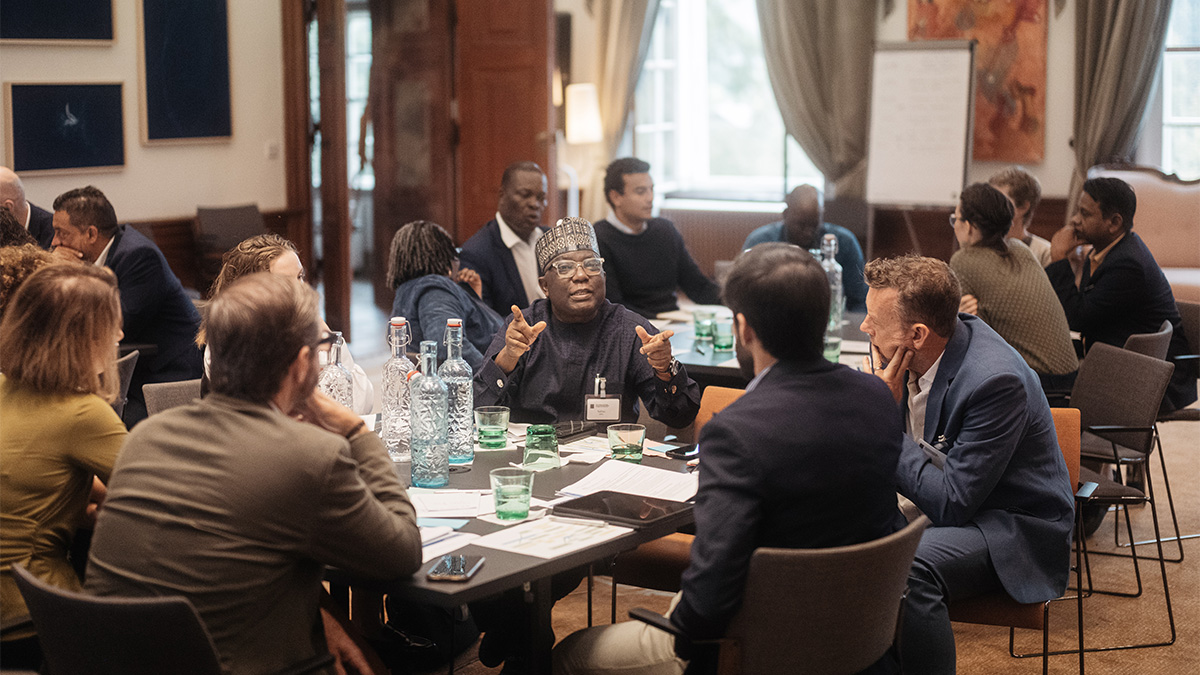 A group of people engaged in a collaborative discussion around a table in the Gallery of Schloss Leopoldskron.